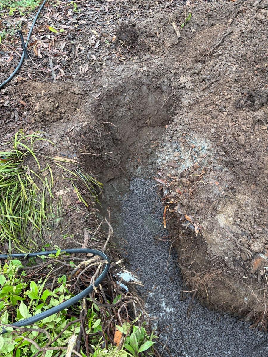 Gravel backfill along the repaired drain line through the garden bed